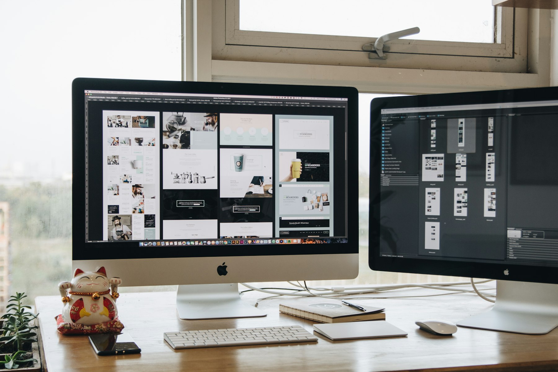 Two computer monitors on a desk showing website layouts